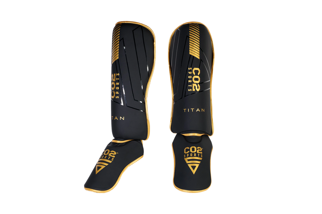 Black and gold shinguards with 'CO2 Sports' branding on a white background
